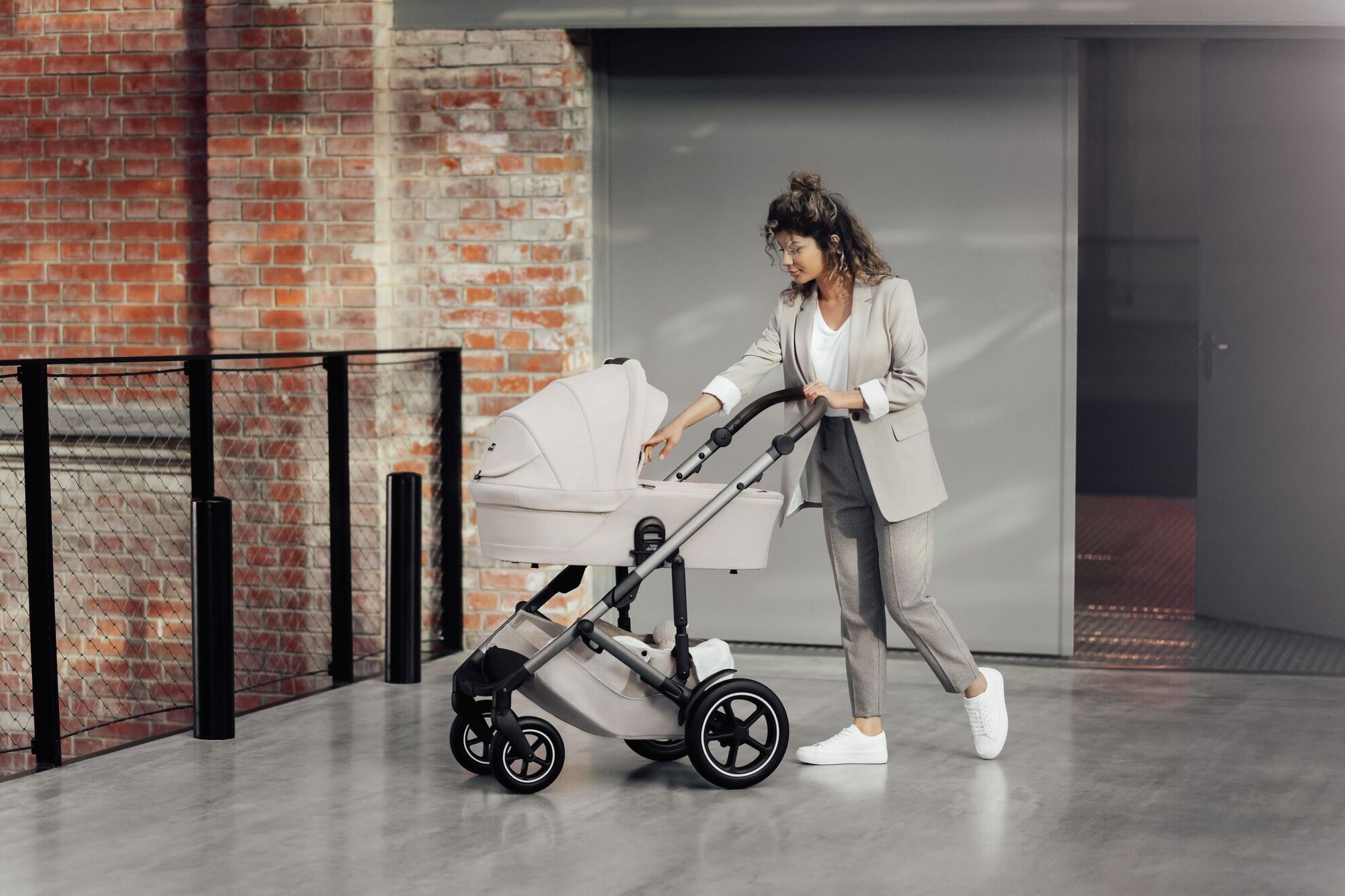 Parent poussant une poussette SMILE 5Z avec nacelle, vérifiant doucement le bébé.